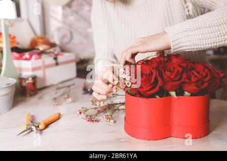 Blumenladen Floristin Herstellung Box mit roten Rosen. Prozess der Erstellung Hut-Box mit Blumen Stockfoto