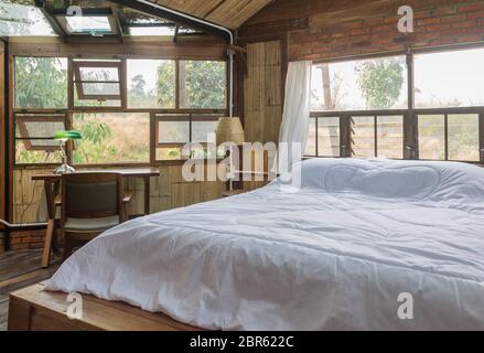 Weiß Bett und Arbeitstisch in Land Interior Design Zimmer Stil. Interior Design Zimmer gehören Stuhl und Lampe. Interior Design Zimmer in Teil von Schlafzimmer Stockfoto