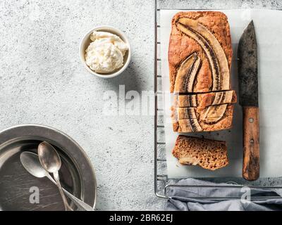 Butter, Zucker-freien Bananenbrot mit Hafermehl, weiche Quark und Honig. Blick von oben auf die bananenscheiben Brot auf grauzement Hintergrund. Ideen und Stockfoto