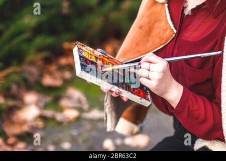 Die Künstlerin hält Aquarellfarben in der Hand. Stockfoto