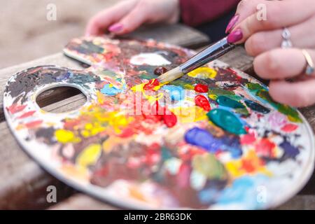 Der Künstler, der ein Bild im Park malt, mischt die Farben auf einer Palette Stockfoto