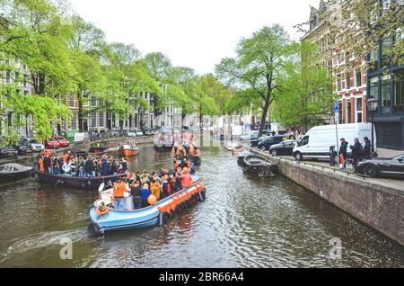 Amsterdam, Niederlande - 27. April 2019: Partyboote mit Menschen in Nationalorange gekleidet, während der Königstag, Koningsdag, dem Geburtstag des niederländischen Königs Willem-Alexander, gefeiert wird. Stockfoto