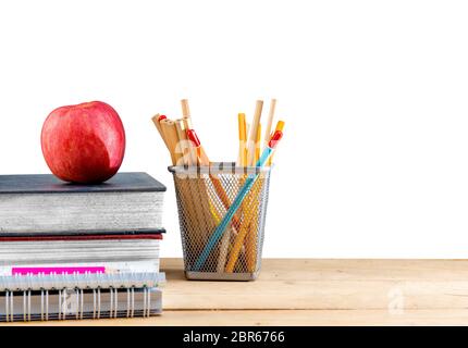 Stapel Bücher mit Apple und Bleistifte in Korb Container auf Holztisch auf weißem Hintergrund. Zurück zu Schule Konzept Stockfoto