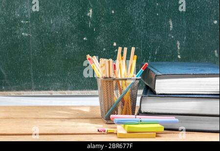 Stapel Bücher mit Stift und Papier mit Bleistift im Korb Container auf Holztisch mit schiefertafel Hintergrund. Zurück zu Schule Konzept Stockfoto