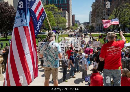 Lansing, Michigan, USA. Mai 2020. Die Leute stellen sich als Barber geben kostenlose Haarschnitte auf dem Rasen des Michigan State Capitol. "Operation Haircut" war ein Protest gegen die Notbestellungen von Gouverneur Gretchen Whitmer, die viele Geschäfte während der Coronavirus-Pandemie geschlossen halten. Der Protest wurde von der Michigan Conservative Coalition organisiert. Kredit: Jim West/Alamy Live News Stockfoto