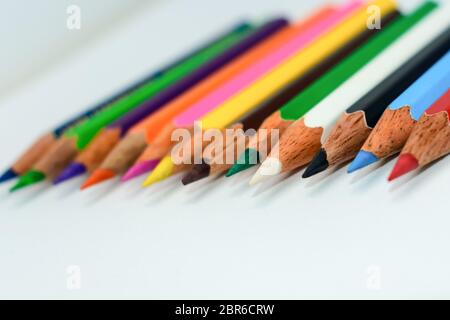 Nahaufnahme einer Auswahl von Multi Buntstifte Buntstifte, halten zusammen in eine Zeile Zeile Balken auf weißem Hintergrund angeordnet, flach. Selektive foc Stockfoto