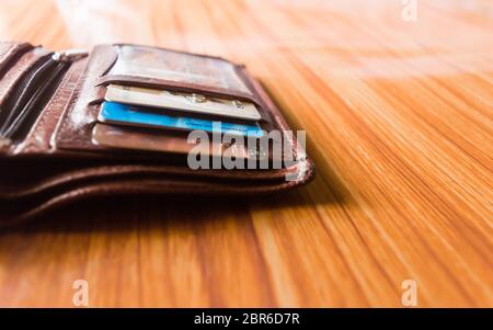 Debit- oder Kreditkarten in einer Ledertasche schön platziert am Holztisch, Studioaufnahme mit Kopieraum Platz für Text auf der rechten Seite. Stockfoto