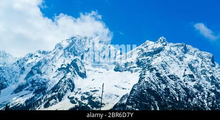 Breites Panorama der schneebedeckten Gipfel und blauen Himmel mit Wolken in Baisaran Tal (Mini Schweiz), Pahalgam, Kaschmir, Indien Stockfoto