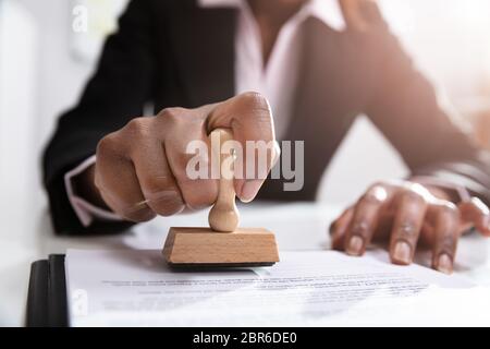 Nahaufnahme der Geschäftsfrau Stempel setzen auf Dokumente im Büro Stockfoto