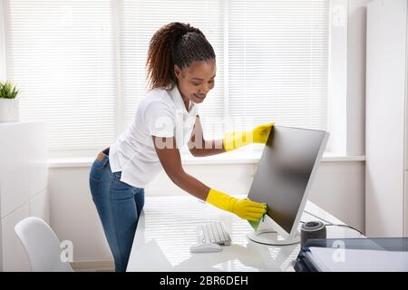 Nahaufnahme von einer Frau Hand Reinigung Desktop Bildschirm mit grünen Rag im Büro Stockfoto