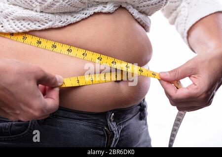 Mittelteil der Frau messen Ihren Bauch mit gelbem Maßband Stockfoto