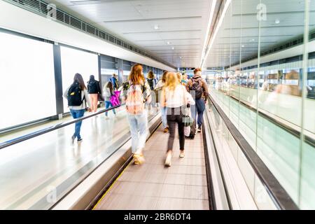 Unkennbarer Flughafen und unkenntliche Menschen, die auf ihren Flug gehen, langer Korridor mit beweglicher Gehweg, Bewegungsunschärfe Stockfoto