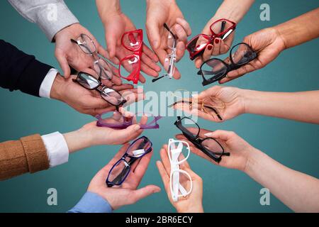 Blick von oben auf die Menschen an der Hand, die Vielzahl von Brillen gegen grüne Kulisse Stockfoto