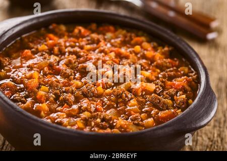 Hausgemachte vegane Sauce Bolognese mit Soja Fleisch, frischen Tomaten, Zwiebeln und Knoblauch, im rustikalen Schüssel serviert (selektive Fokus, Fokus ein Drittel in die Stockfoto