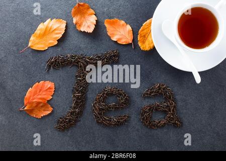 Lose schwarzer Tee Blätter Rechtschreibung Kaffee auf Schiefer, Herbstblätter und Tasse schwarzen Kaffee an der Seite, fotografiert Overhead auf Schiefer (selektive Fokus, Fokus o Stockfoto