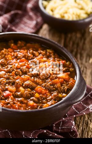 Hausgemachte vegane Sauce Bolognese mit Soja Fleisch, frischen Tomaten, Zwiebeln und Knoblauch, im rustikalen Schüssel serviert, gekochten Nudeln in der Rückseite (selektive Fokus, Stockfoto