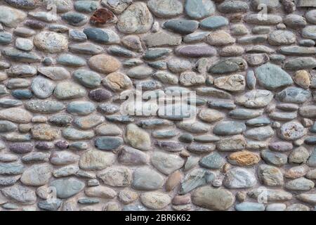 Wand mit bunten zementiert Kieselsteinen. Es kann als Hintergrund verwendet werden. Stockfoto