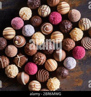 Gourmet Specialty Schokolade Bonbons oder Pralinen in einem ordentlichen Rechteck auf rustikalem Holz Tisch arrangiert Gesehen von oben nach unten Stockfoto