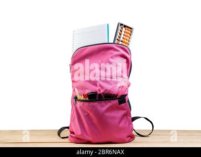 Rosa Rucksack mit Buch- und anderen Schreibwaren auf Holztisch auf weißem Hintergrund. Zurück zu Schule Konzept Stockfoto
