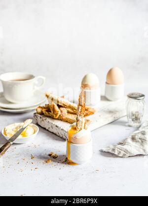 Weich gekochtes Ei Frühstück mit Soldaten serviert mit Kaffee Stockfoto