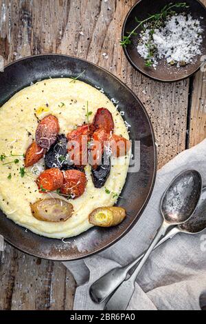 Vegane cremige Polenta mit gerösteten Mossälen auf Holzgrund. Stockfoto