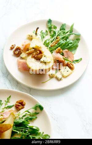 Birnensalat mit Walnüssen, Prosciutto, Rucola und Blauschimmelkäse. Abendessen Vorspeise auf Marmortisch Stockfoto