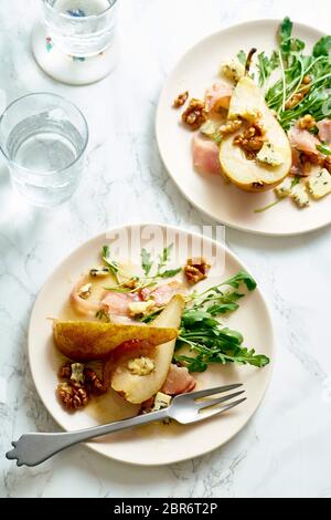 Birnensalat mit Walnüssen, Prosciutto, Rucola und Blauschimmelkäse. Abendessen Vorspeise auf Marmortisch Stockfoto