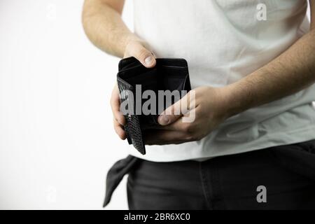 Kaukasischer Mann mit leeren Taschen hält eine leere Brieftasche ohne Geld. Stockfoto