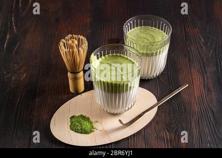 Matcha grüner Tee Latte, Matcha Pulver und Bambus Schneebesen auf Holz Hintergrund. Draufsicht. Stockfoto