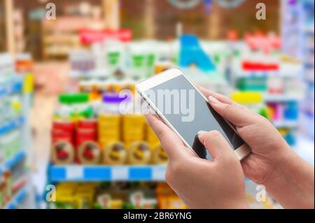 Apotheke und Drogerie-Konzept, Hand Frauen mit Smartphone in Apotheke auf unscharfen Hintergrund Stockfoto