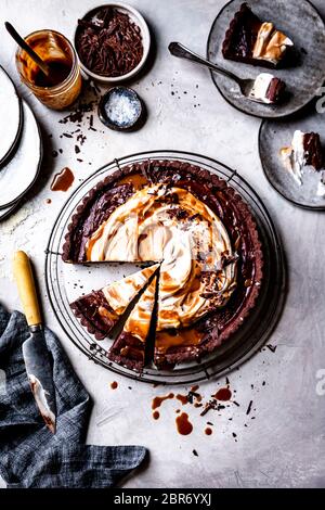 Karamelltarte aus Schokolade mit Scheiben auf Tellern. Stockfoto