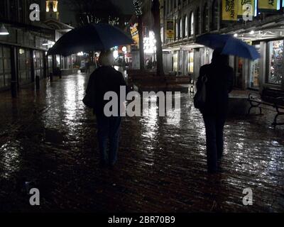 Zwei Frauen, die im Regen im historischen Viertel von Boston Massachusetts mit Regenschirmen spazieren. Stockfoto