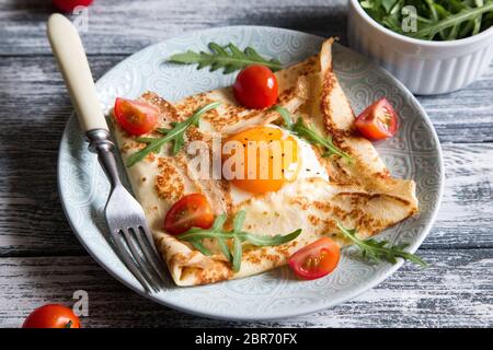 Crepes mit Eiern, Käse, Rucola Blätter und Tomaten. Galette abgeschlossen. Traditionelles Gericht galette Sarrasin Stockfoto