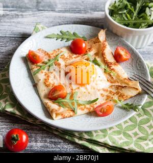 Crepes mit Eiern, Käse, Rucola Blätter und Tomaten. Galette abgeschlossen. Traditionelles Gericht galette Sarrasin Stockfoto