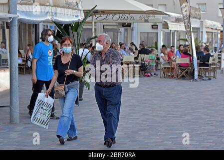 Calafell, Tarragona, Spanien. Mai 2020. Ein Paar trägt als Vorsichtsmaßnahme Gesichtsmasken, Spaziergang entlang Paseo Maritmo Straße während des Endes der Enge der Phase One.Calafell ist in Phase eins des Endes der Enge, aber mit strengen Maßnahmen, wo Sie auf den Terrassen der Restaurants mit den Sicherheitsmaßnahmen von 2 Metern zwischen den Tischen sein können, Gehen Sie am Strand spazieren, aber nicht auf dem Sand sitzen oder baden. Die örtliche Polizei führt Straßenkontrollen durch, um die Einhaltung der Vorschriften zu kontrollieren. Quelle: Ramon Costa/SOPA Images/ZUMA Wire/Alamy Live News Stockfoto