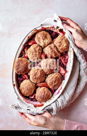 Cranberry und Apfelpflasterin in einer Hand gehalten Backform. Stockfoto