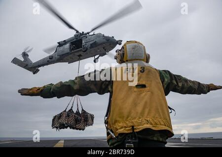 200514-N-WO152-0128 ATLANTISCHER OZEAN (14. Mai 2020) Aviation Boatswain's Mate (Handling) Isaiah Johnson der 3. Klasse aus Manchester, New Jersey, leitet einen MH-60S Sea Hawk Hubschrauber, der dem "Dragon Slayers" der Helicopter Sea Combat Squadron (HSC) 11 zugewiesen wurde, auf dem Flugdeck des Nimitz-Klasse Flugzeugträgers USS Harry S. Truman (CVN 75) während einer Wiederauffüllung auf See im Atlantischen Ozean 14. Mai 2020. Die Harry S. Truman Carrier Strike Group (HSTCSG) bleibt als zertifizierte Trägerstreikgruppe auf See, die bereit ist, die Besatzung vor den Risiken zu schützen Stockfoto