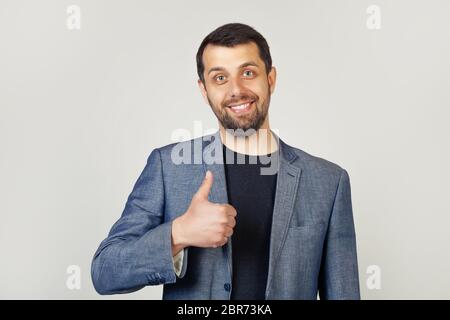 Junger Mann mit Borsten Geschäftsmann zeigt Finger bis zur Kamera mit einem glücklichen Lächeln. Alles ist gut, zeigt Erfolg. Stockfoto