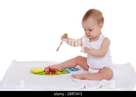 Süßes Baby in Windel spielt mit buntem Xylophon (Musikinstrumentspielzeug für Kinder) auf weißem Hintergrund. Frühe Entwicklung und Lernspielzeug Stockfoto