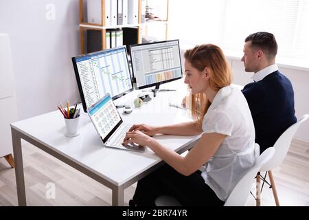 Zwei Geschäftsleute sitzen auf Stuhl Arbeiten im Büro mit Computer und Laptop Stockfoto