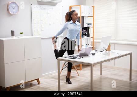 Junge Geschäftsfrau Yoga Vor Büro Schreibtisch Stockfoto