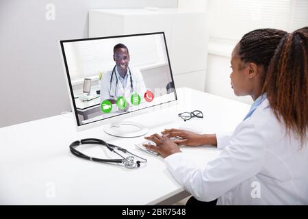 Ärztin Videokonferenzen mit glücklichen männlichen Kollegen auf dem Computer über Schreibtisch Stockfoto
