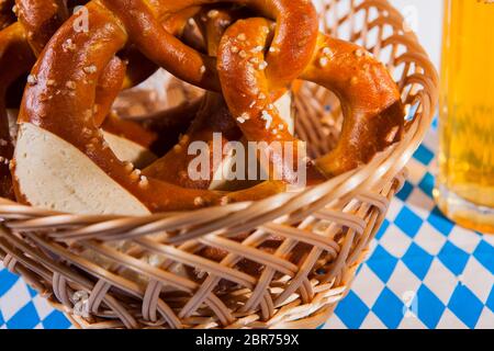 Das Foto zeigt einen Brotkorb mit frischen Brezeln und ein Glas Bier Stockfoto