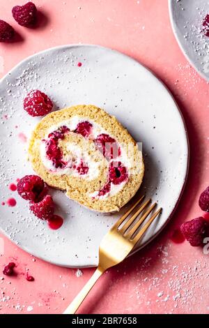 Himbeer-Biskuit-Rollkuchen auf einem Teller mit Gabel. Stockfoto