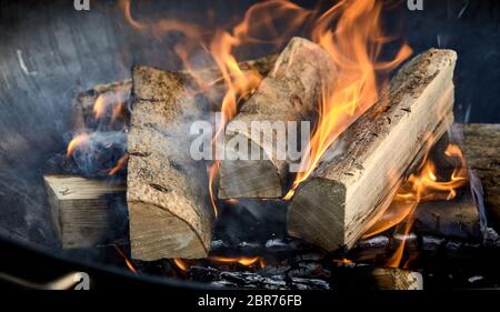 Vor kurzem leuchtet Feuer mit Logs von flammenden Holz auf einem Bett von gehackten Kindling in einem tragbaren Sommer Grill in der Nähe zu Panorama banner anzeigen Stockfoto