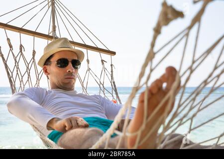 Close-up ein Mann mit Sonnenbrille liegen auf Hängematte Vor der Meer am Strand Stockfoto