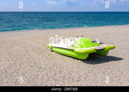 Grüne Tretboot auf dem Kies Strand am Tyrrhenischen Meer in Kalabrien, Italien Stockfoto