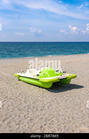 Grüne Tretboot auf dem Kies Strand am Tyrrhenischen Meer in Kalabrien, Italien Stockfoto