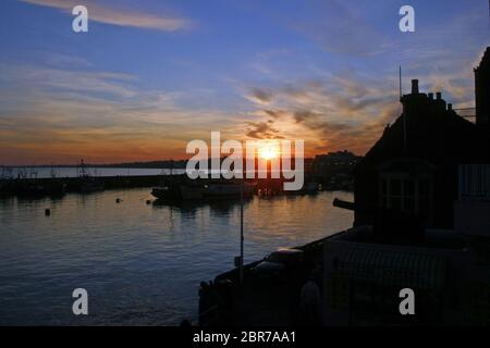 Sonnenuntergang vom Hafen Bridlington in East Yorkshire mit stillem Wasser und Fischerbooten. Stockfoto