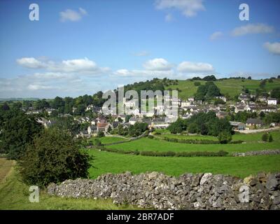 Blick auf das Dorf Brassington in Derbyshire mit der Kirche in der Ferne und Felder mit Trockenmauern im Vordergrund. Typische Kante der Th Stockfoto